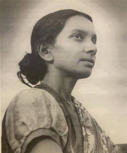 Archival photograph of Kalpana Datta in a patterned sari, standing outdoors and looking upward past the camera.