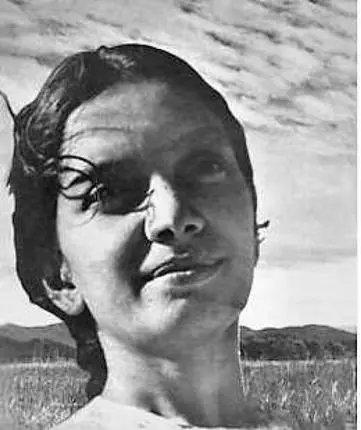 Archival photograph of Kalpana Datta outdoors with clouds and an open field behind her, her head turned slightly to one side.